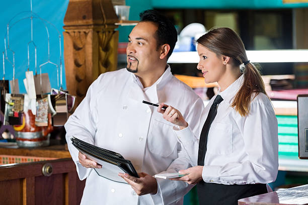 Chef And Waitress Talking Near Commercial Kitchen In Restaurant